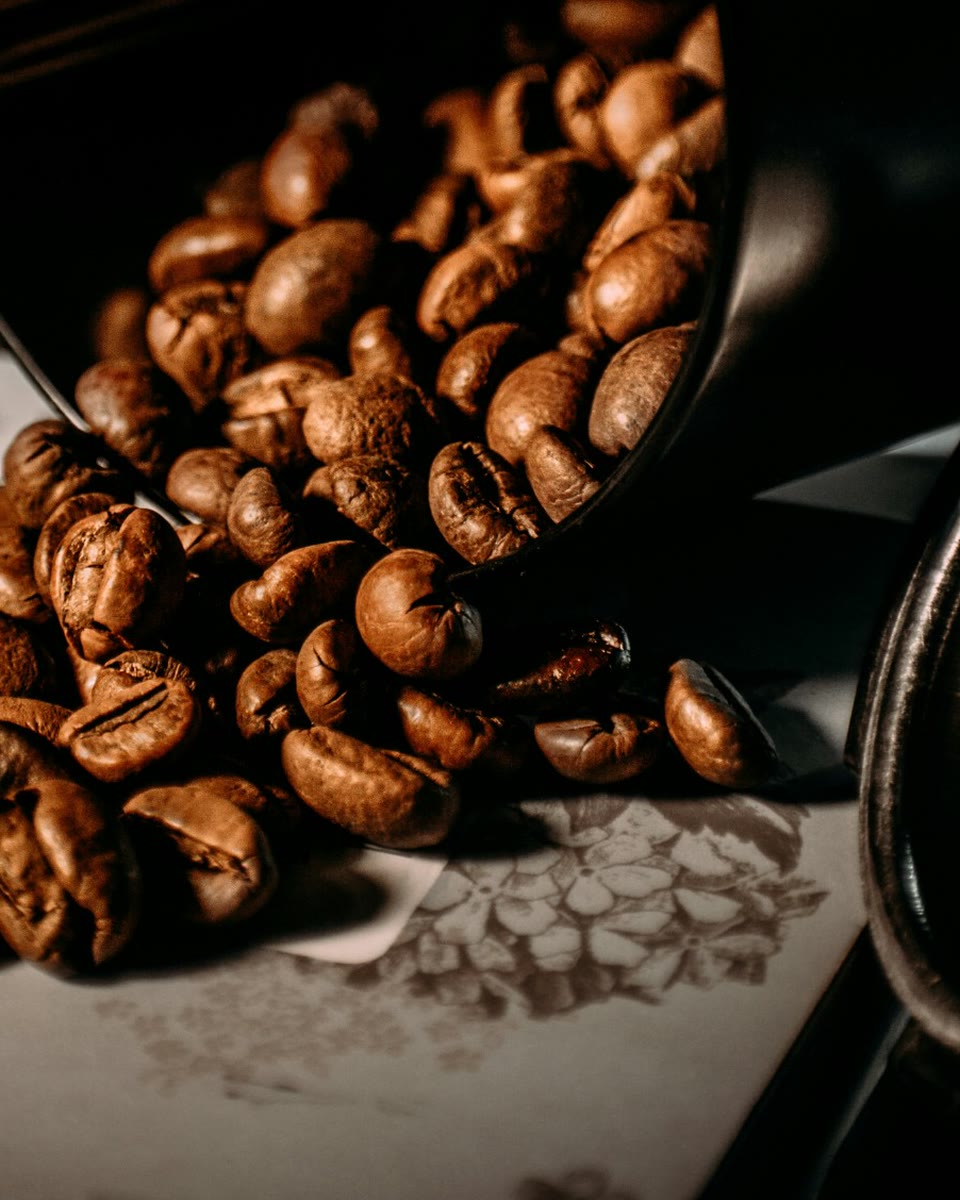 Roasted coffee beans spilling from a dark tin